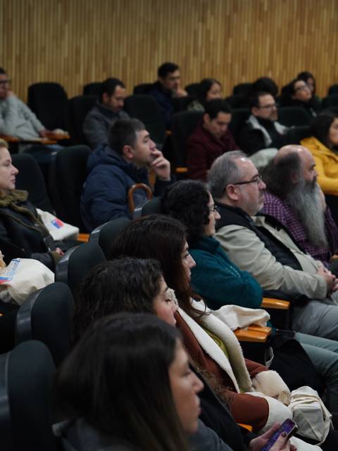Un grupo de personas sentadas en una sala de conferencias escuchando atentamente.