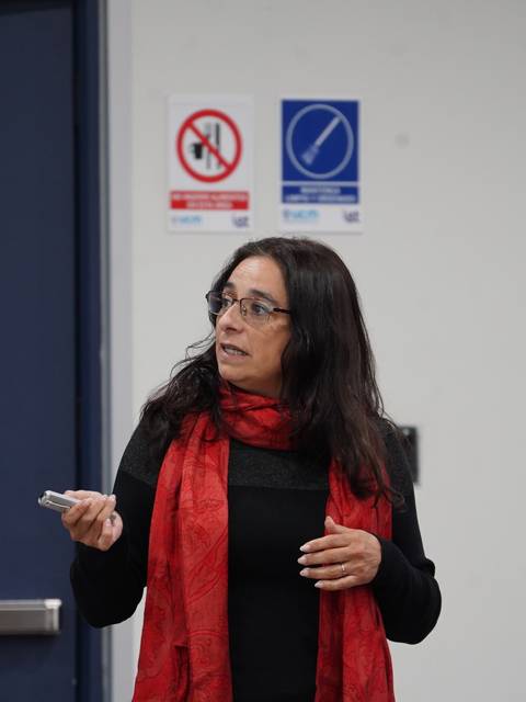Una mujer con una bufanda roja está presentando en una sala.