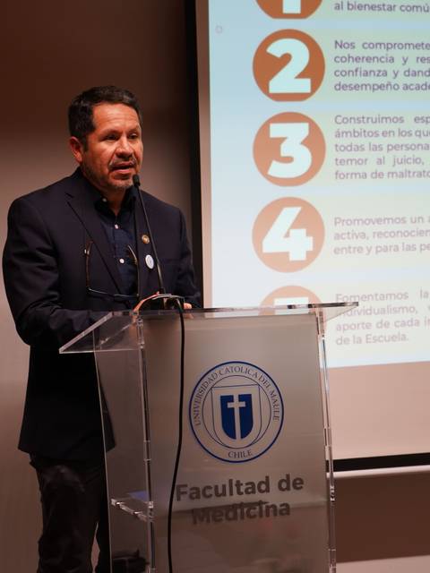 Un hombre presenta en la Facultad de Medicina, destacando la importancia de la colaboración en la educación.