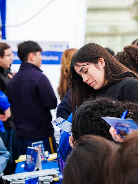 Un grupo de estudiantes está interactuando en un evento de orientación o feria en Chile.