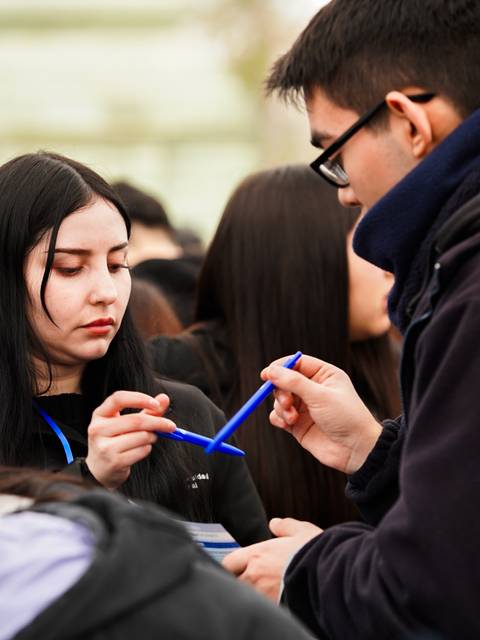 Un grupo de jóvenes interactuando en un evento, enfocándose en compartir materiales.