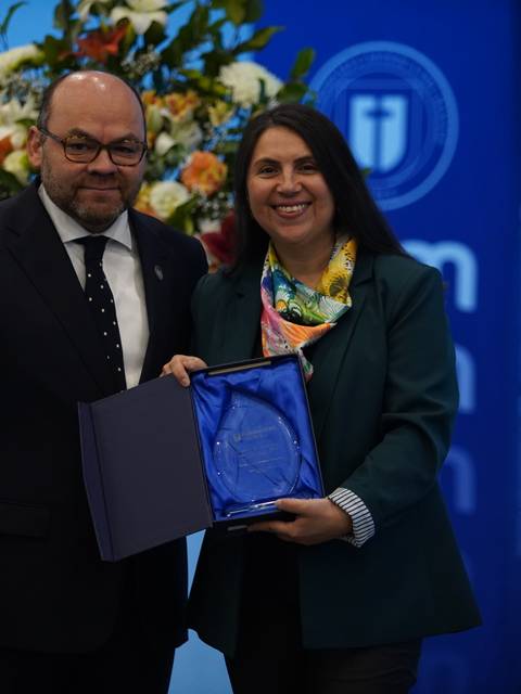 Una pareja de personas sonríe mientras sostienen un premio en un evento formal.