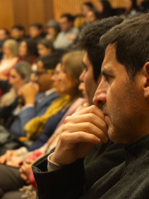 Un grupo de personas sentadas en un auditorio prestando atención a una charla.