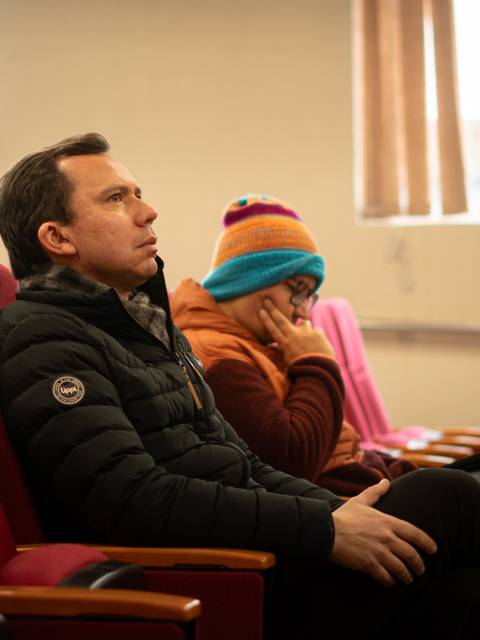 Una persona sentada en una sala de espera, mirando hacia el frente con expresión seria.