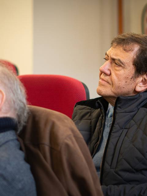 Un grupo de hombres mayores escuchando atentamente en una charla.