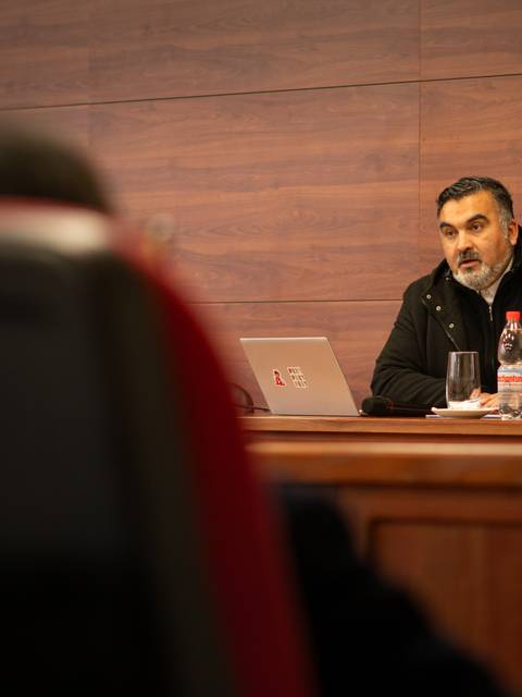 Un hombre con barba discurso en una reunión formal.