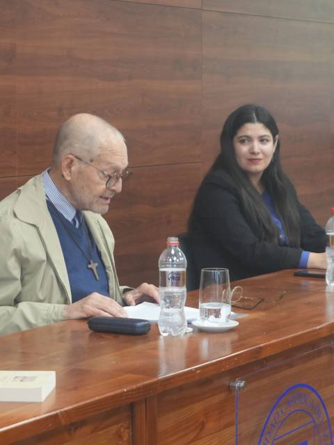 Un anciano y una mujer joven participan en una charla en un salón de conferencias.