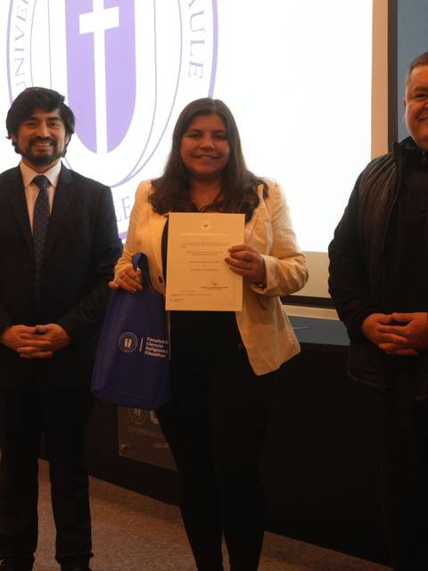Tres personas posando después de una ceremonia de entrega de certificados en una universidad chilena.