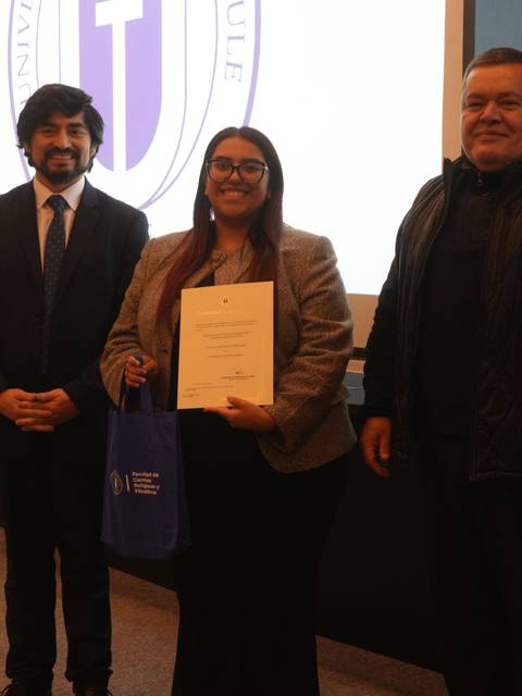 Tres personas posan en un evento académico de la Universidad de Chile.