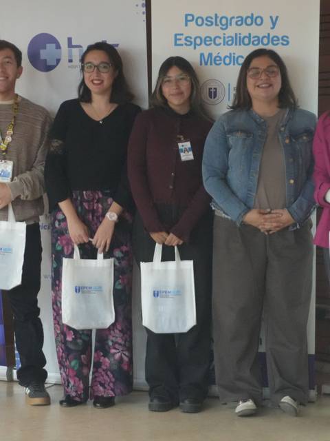 Un grupo de personas sonrientes posando en un evento con bolsas blancas en las manos.