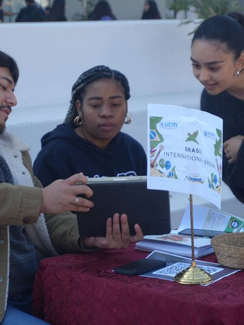 Tres jóvenes conversando sobre un proyecto en una feria.