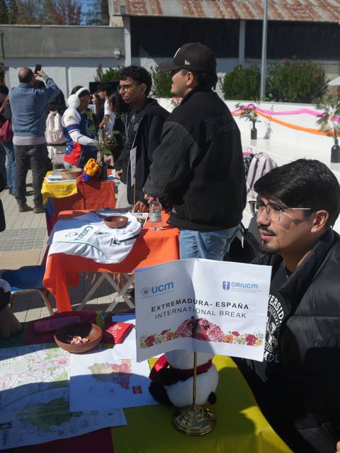 Una feria estudiantil con stands y estudiantes conversando entre ellos.