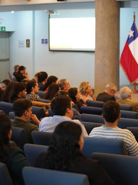 Un grupo de personas sentadas en una sala durante un evento en Chile.