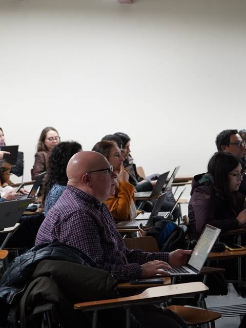 Una clase llena de estudiantes concentrados en sus computadores.