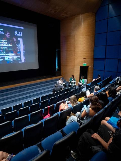 Una sala de cine con un público sentado escuchando a un panel de discusión en el escenario.
