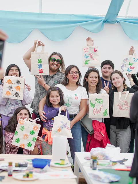 Un grupo de personas sonrientes sostiene sus bolsas artesanales en un taller creativo.