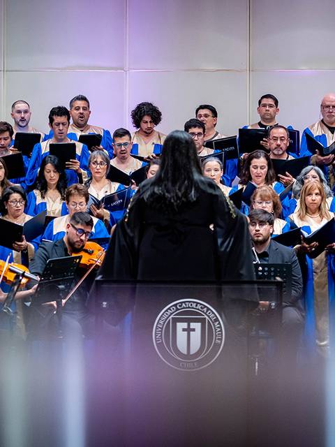 Un coro en plena actuación, con músicos y cantantes vestidos con túnicas azules en un escenario iluminado.