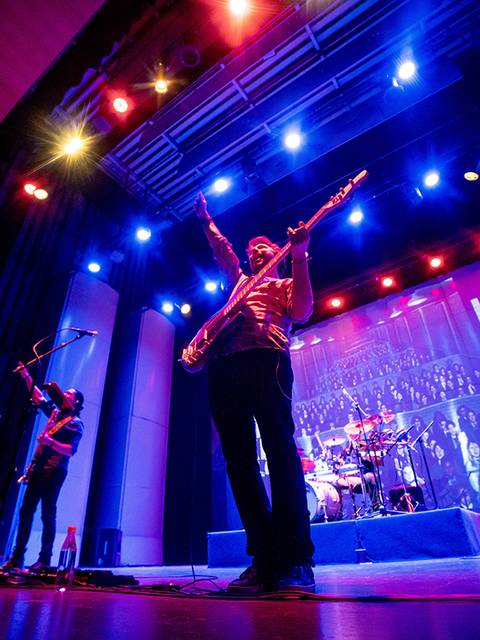 Una banda tocando en un escenario iluminado con luces de colores.