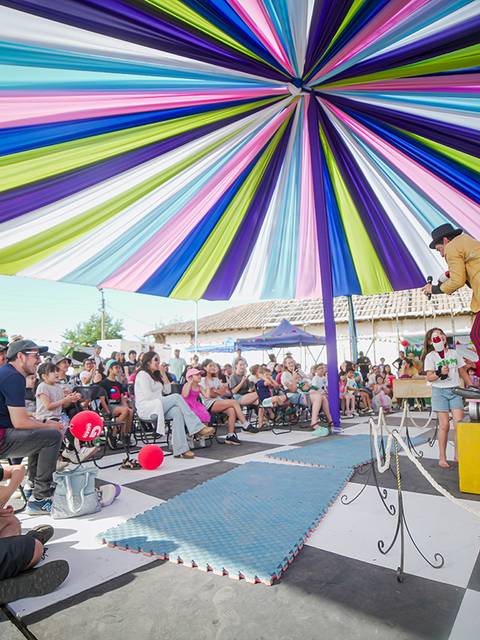 Un espectáculo circense con un público entusiasta bajo una carpa de colores vibrantes.