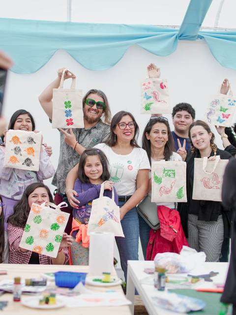 Un grupo de personas posando felices con bolsas decoradas en una actividad creativa.