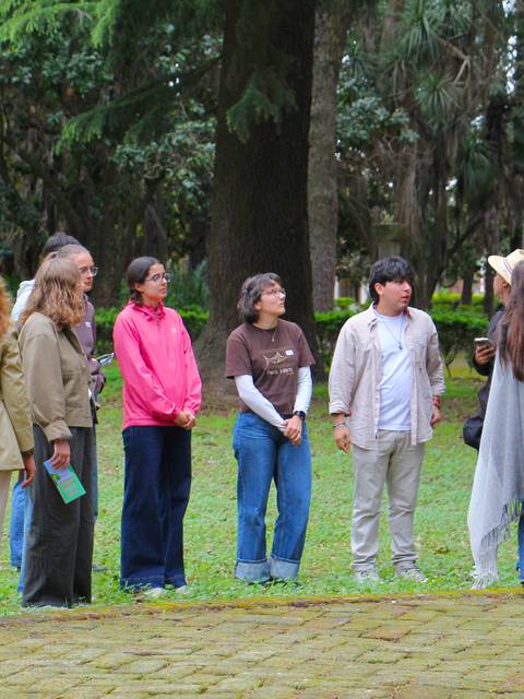 Un grupo de personas escucha atentamente a una guía en un parque.
