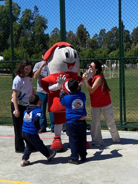 Un grupo de niños interactuando con una mascota en un evento al aire libre.
