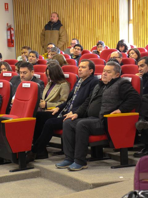 Una audiencia atenta sentada en butacas rojas durante un evento.