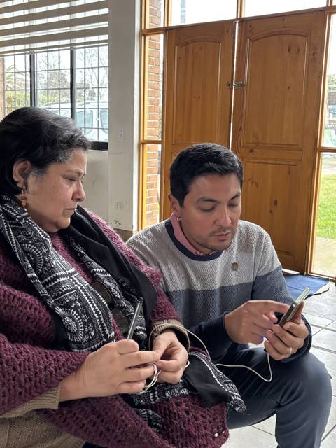 Una mujer y un hombre conversan mientras miran un teléfono en un ambiente acogedor.