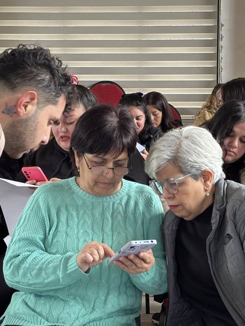 Un grupo de personas se reúne para aprender a usar sus teléfonos en un ambiente colaborativo.