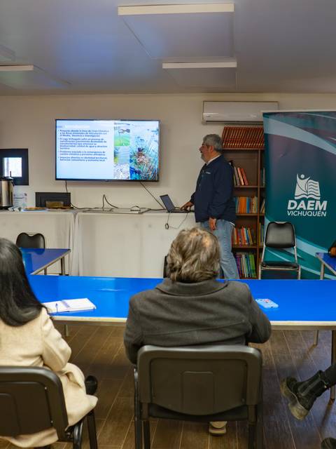 Una presentación en un aula con varios asistentes atentos a un expositor.