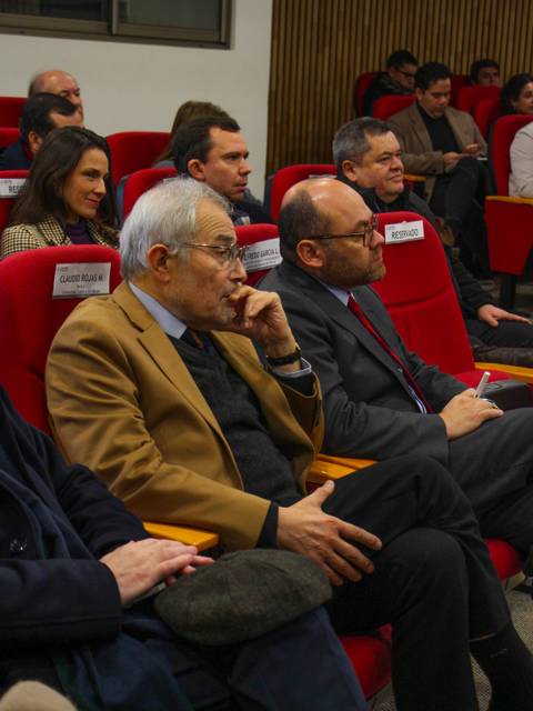 Un grupo de personas sentadas en un evento, escuchando atentamente.