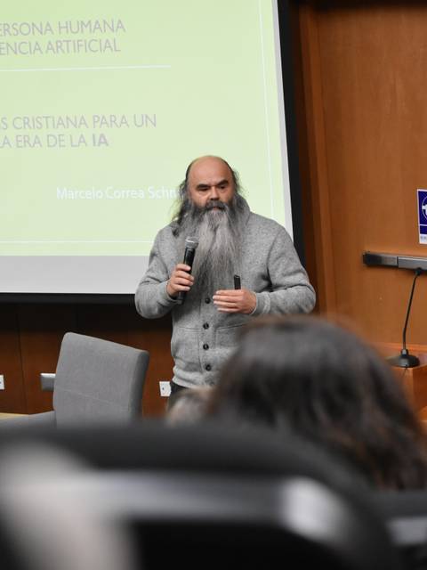 Un expositor con barba larga habla sobre inteligencia artificial en una charla académica.