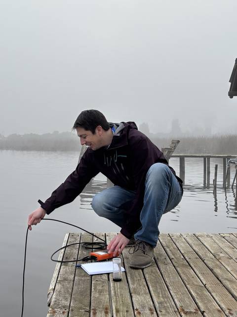 Un cabro chico haciendo medidas en un muelle flotante bajo un clima nublado.
