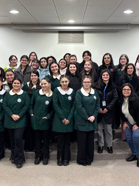 Un grupo de estudiantes y profesionales se reúnen en un evento para celebrar la educación y el empoderamiento femenino.