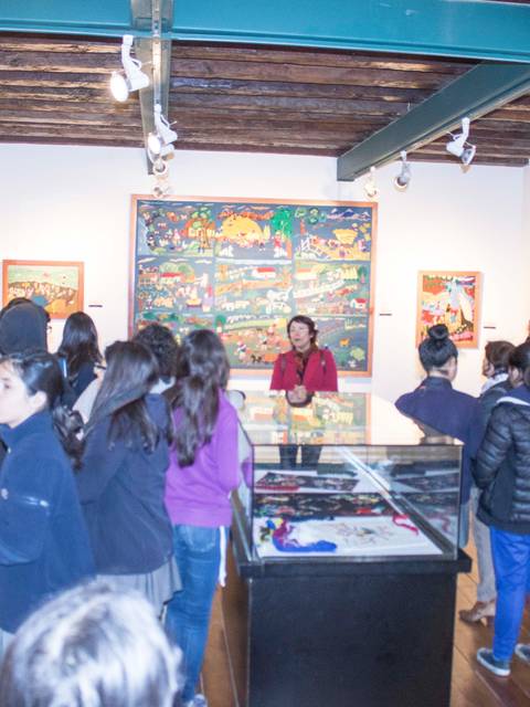 Un grupo de personas observa obras de arte en una galería.