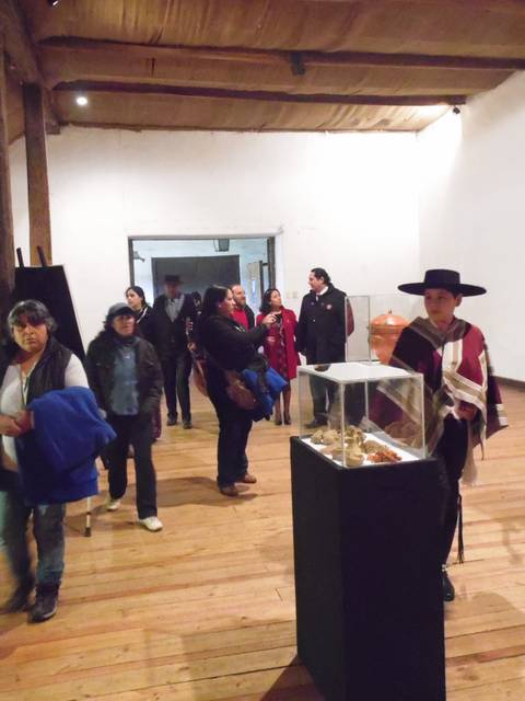 Un grupo de personas camina por un espacio interior de exhibición con paredes blancas y un suelo de madera.