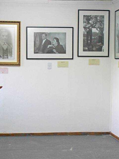 Una mujer de pie en una sala de exposición, rodeada de fotografías enmarcadas.