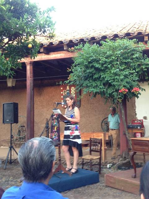 Una mujer está hablando en un evento al aire libre rodeada de espectadores en un entorno rural.