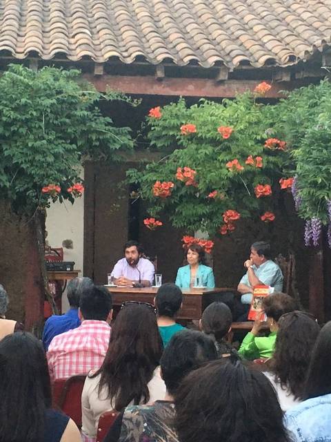 Una charla en un ambiente al aire libre rodeado de flores y plantas.