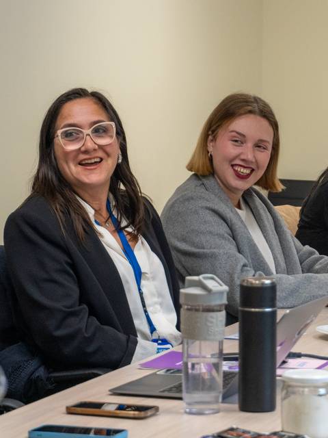 Un grupo de mujeres sonrientes conversando en una reunión.