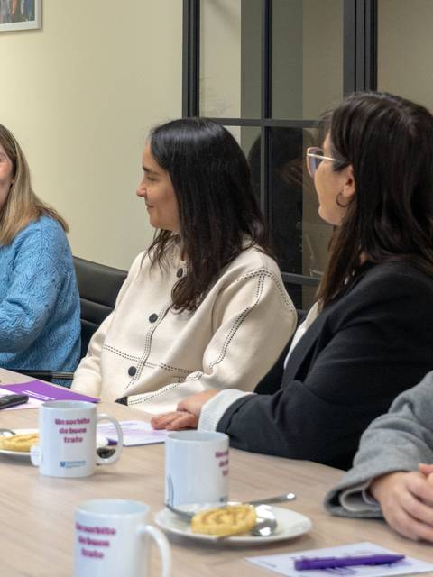 Un grupo de mujeres conversando y disfrutando de una reunión en una oficina.