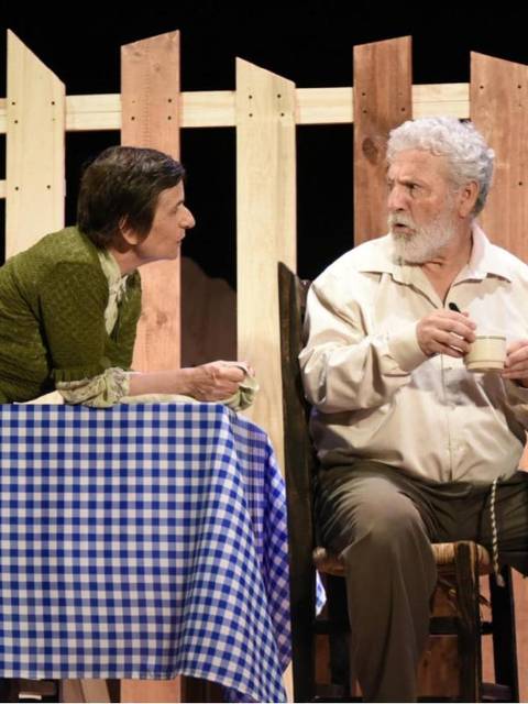 Una pareja se encuentra en una conversación animada en un ambiente teatral chileno.