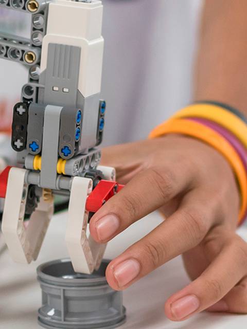 Un robot mecánico está siendo manipulado por una persona que sostiene una pieza en la mano.