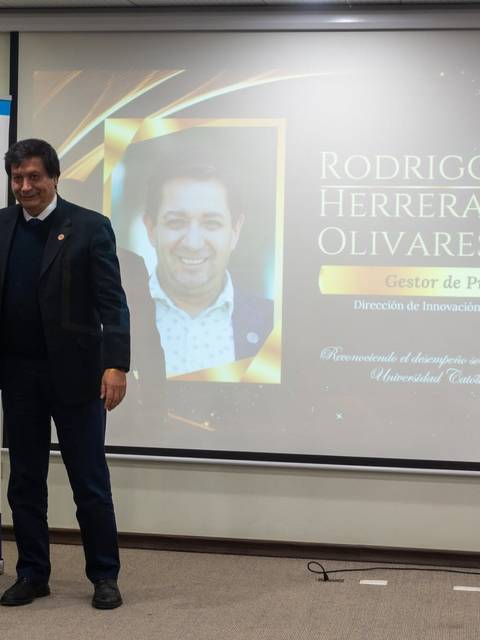 Dos hombres posan felices en un evento de premiación, uno de ellos sostiene un reconocimiento.