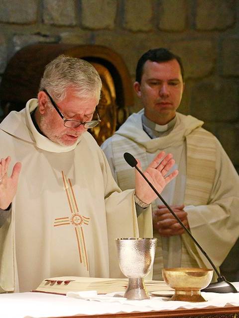 Dos sacerdotes oficiando una ceremonia religiosa en un altar.
