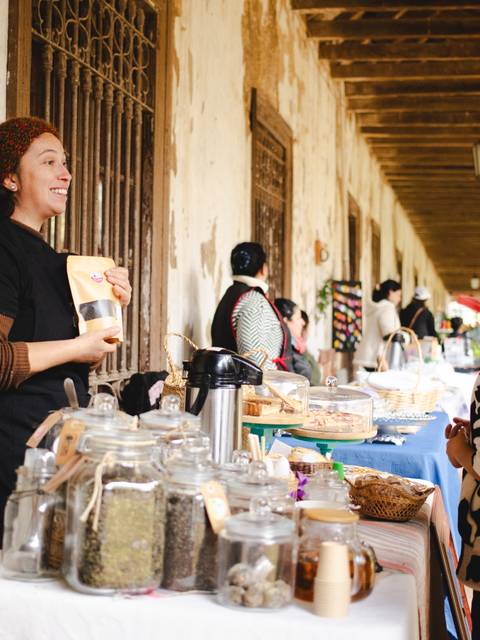 Mujer alegre vendiendo productos en un mercado al aire libre.