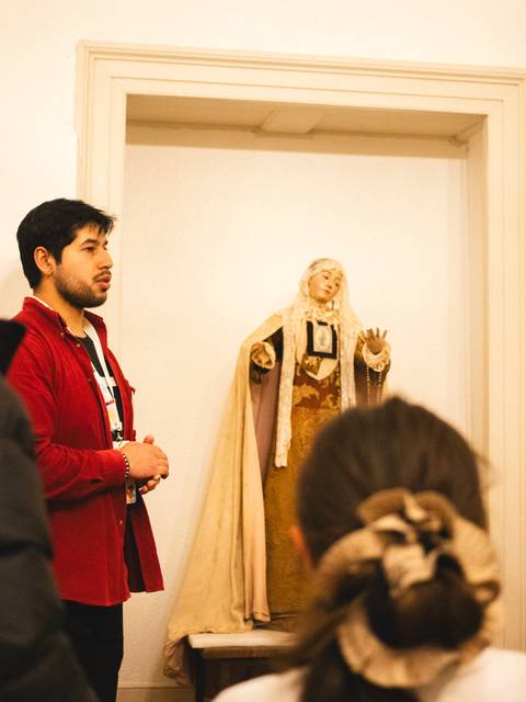Un grupo de personas está escuchando a un guía frente a una estatua en una exposición.