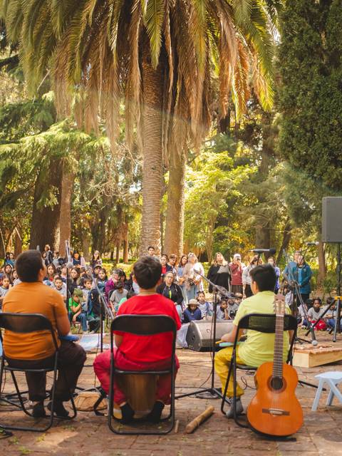 Un grupo de músicos toca en un parque mientras una multitud los escucha atentamente.