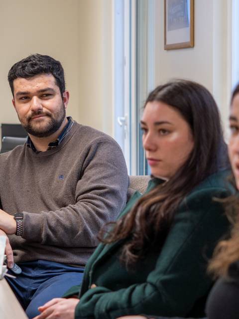 Un grupo de personas sentadas en una mesa de trabajo, conversando y concentradas en una reunión.