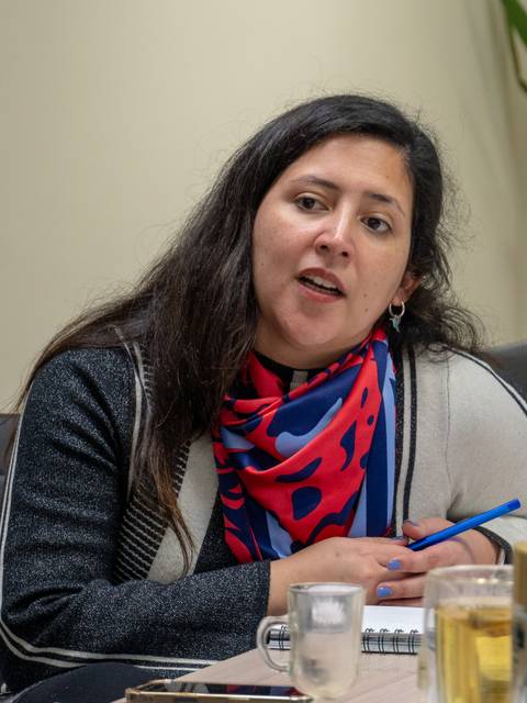 Una mujer con bufanda colorida habla en una reunión.